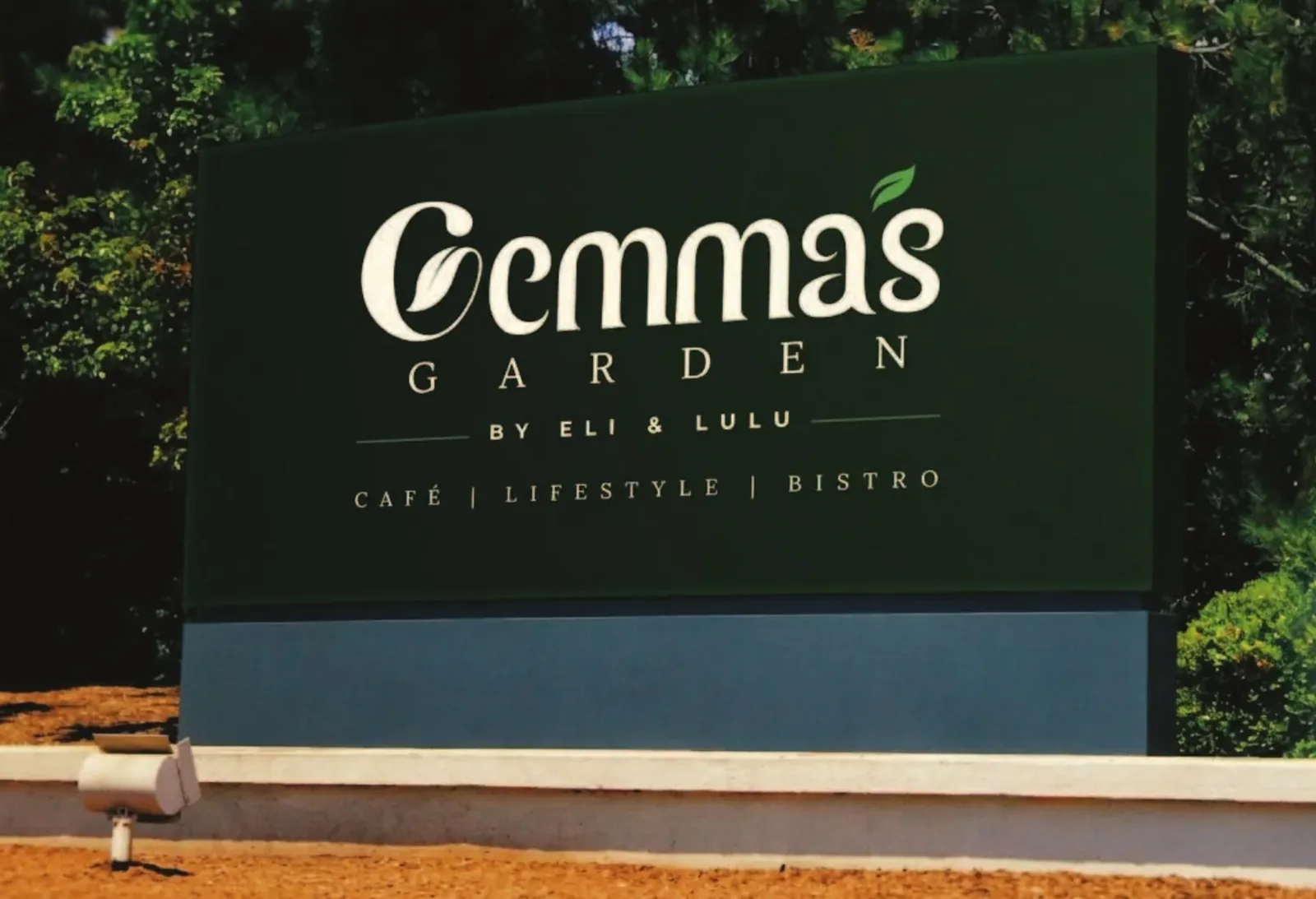 The Gemma’s Garden sign, cream lettering on deep green, set in a garden.